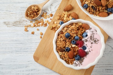 Tasty homemade granola served on white wooden table, flat lay. Healthy breakfast