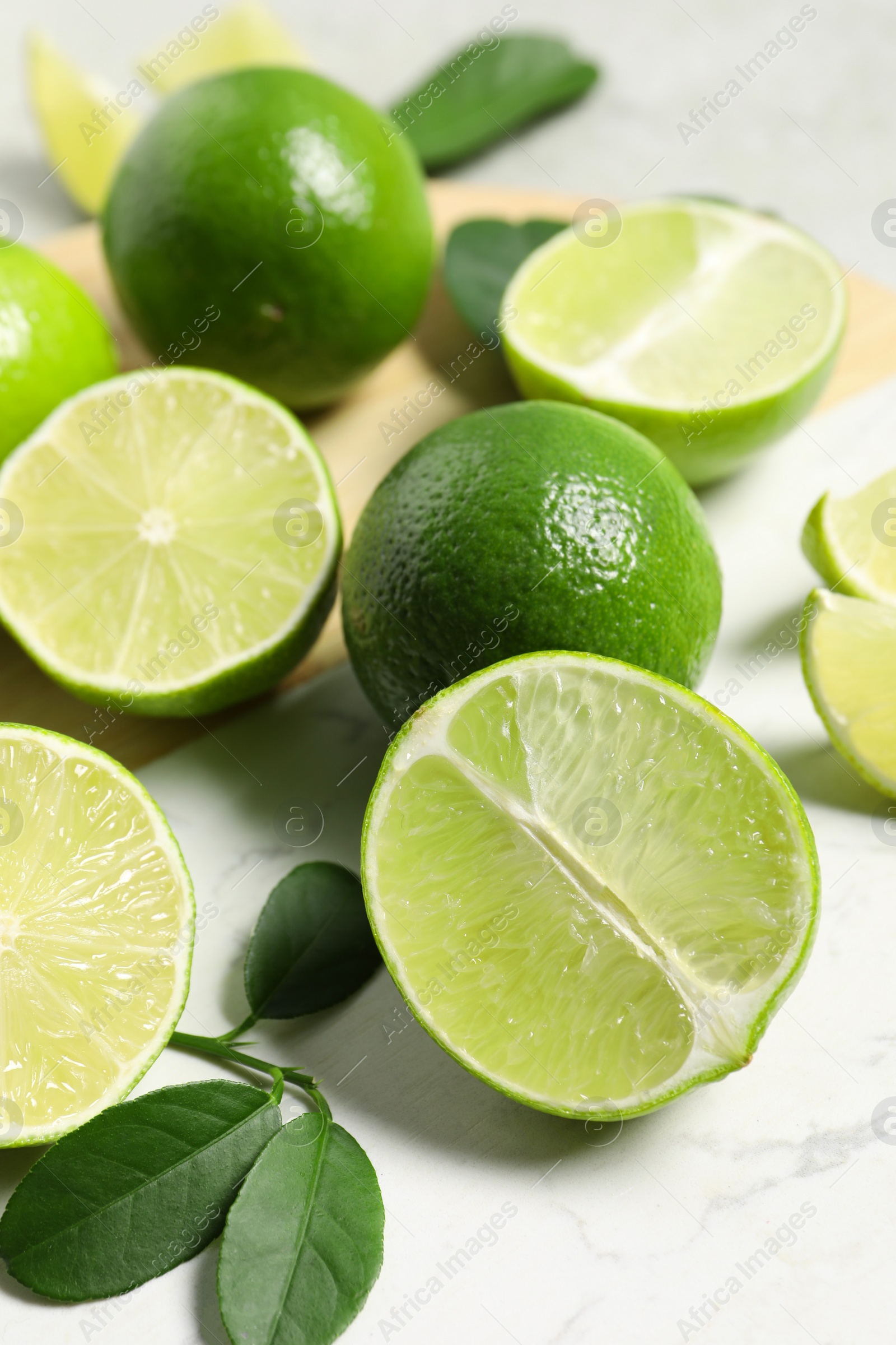 Photo of Fresh ripe limes and leaves on table, closeup