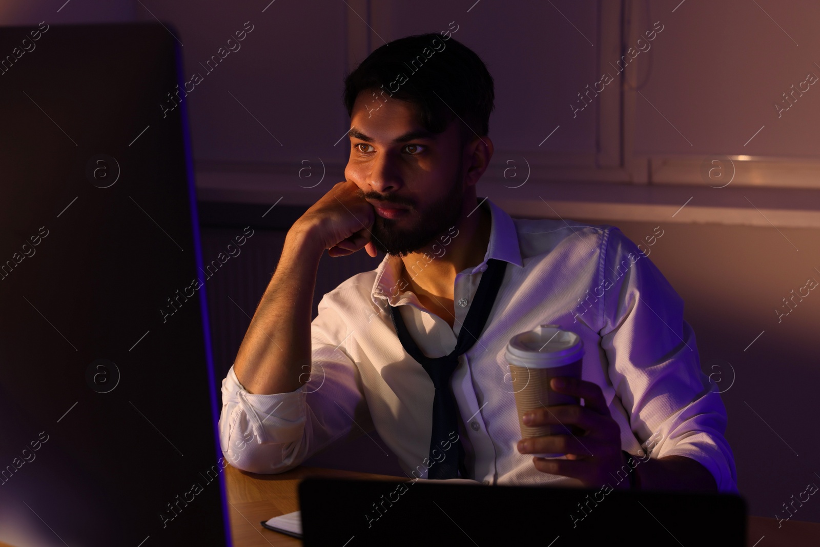 Photo of Tired man with coffee working late in office