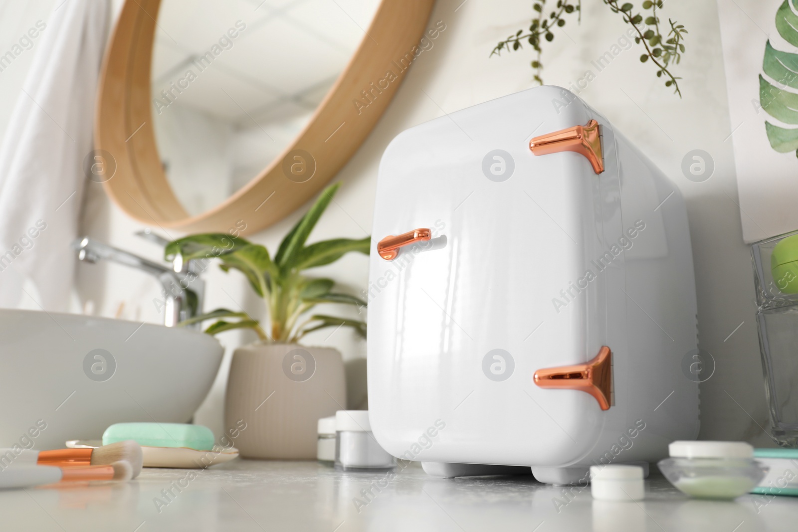 Photo of Cosmetics refrigerator and skin care products on white countertop in bathroom, low angle view