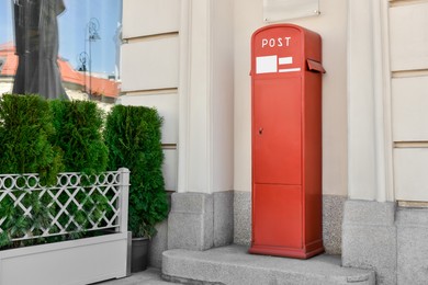 Photo of Red postbox near beige building on summer day