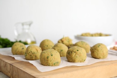 Photo of Raw falafel balls on wooden board, space for text