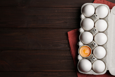 Photo of Fresh raw chicken eggs in box on wooden table, flat lay. Space for text