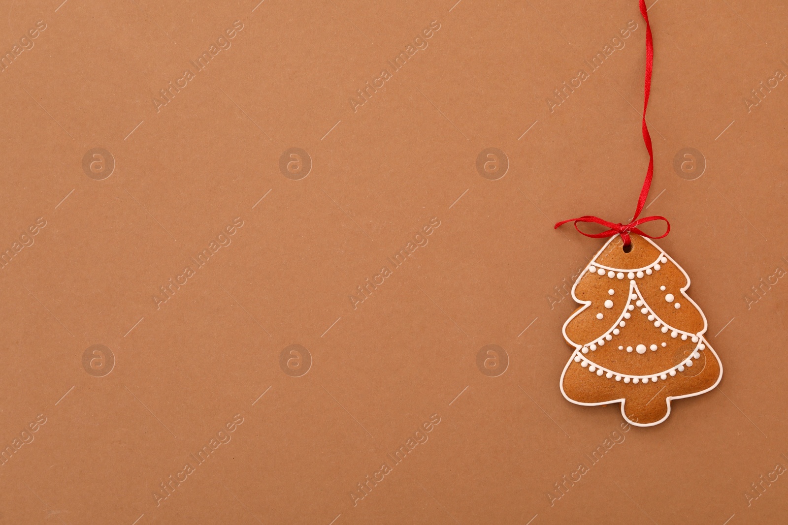 Photo of Christmas tree shaped cookie on brown background, top view. Space for text