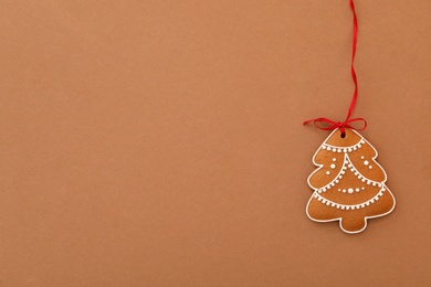 Photo of Christmas tree shaped cookie on brown background, top view. Space for text