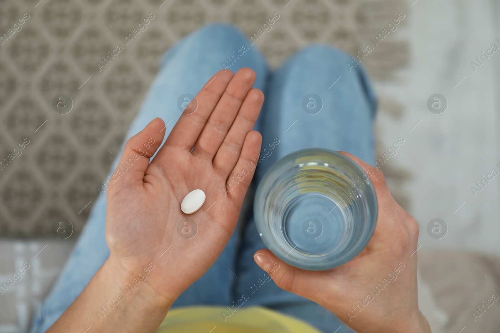 Photo of Young woman with abortion pill and glass of water, top view