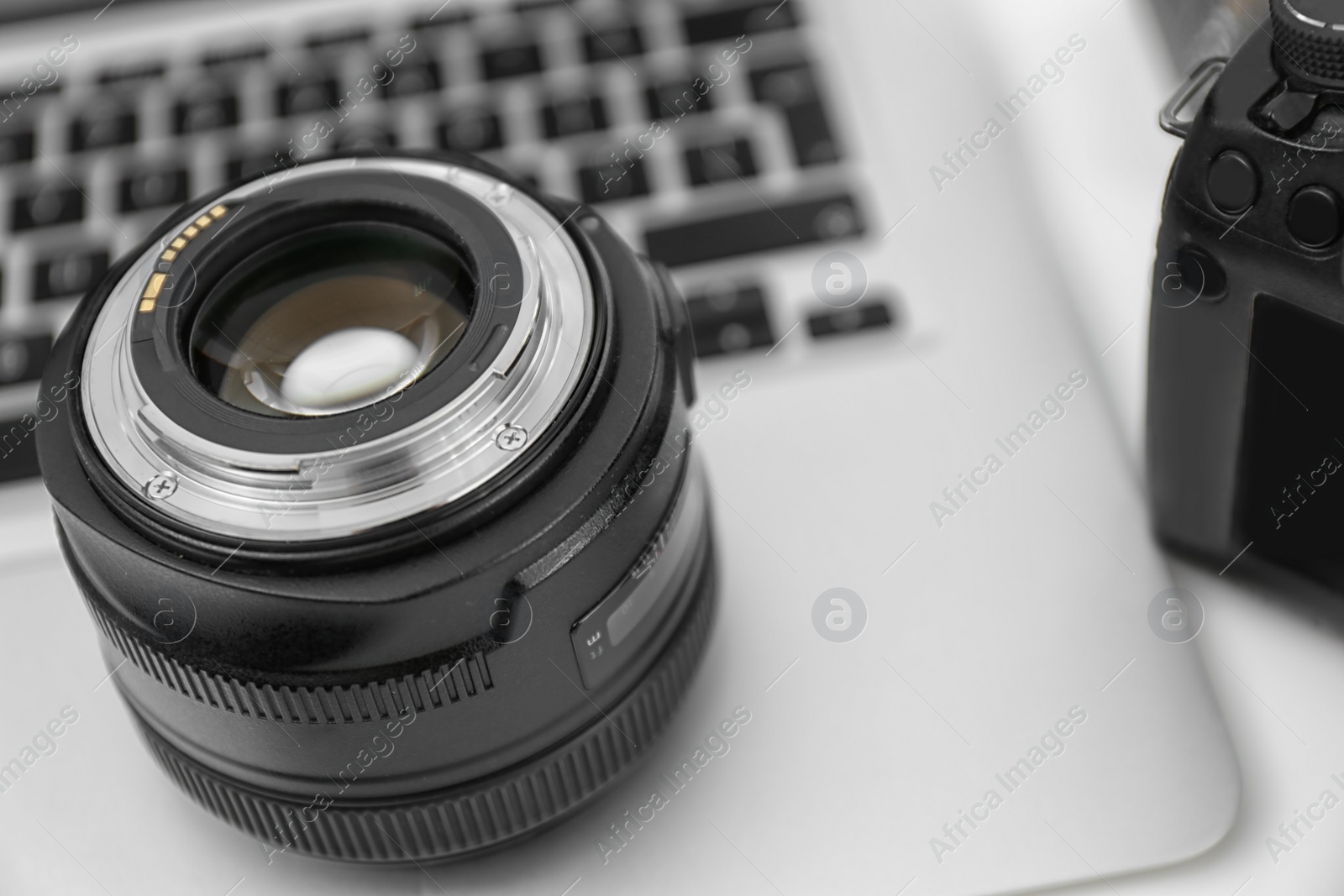 Photo of Camera lens on laptop, closeup. Equipment for professional photographer