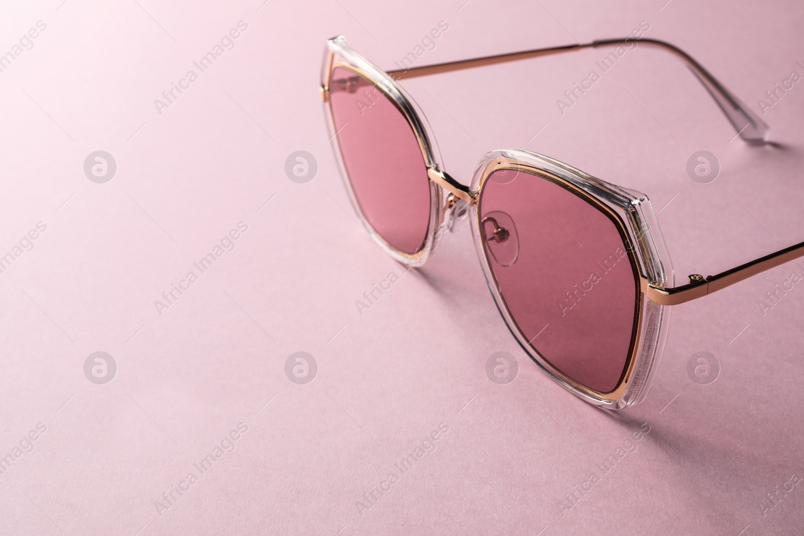 Photo of New stylish sunglasses on pink background, closeup. Space for text