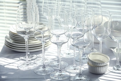 Photo of Set of empty wine glasses and dishware on table indoors
