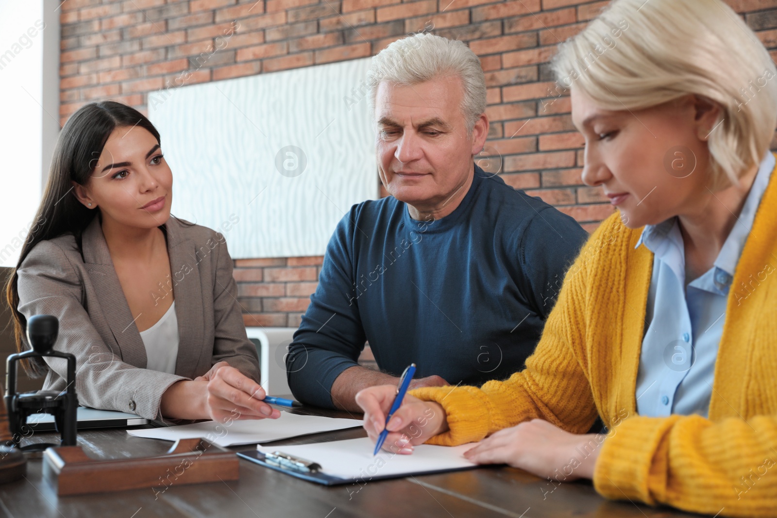 Photo of Female notary working with mature couple in office