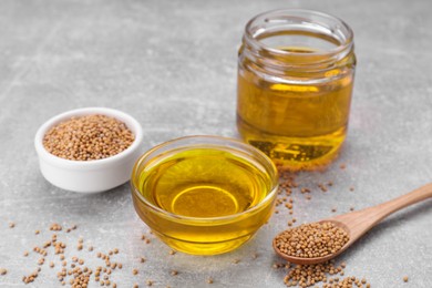 Photo of Natural oil and mustard seeds on light grey table