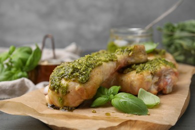 Delicious fried chicken drumsticks with pesto sauce and basil on table, closeup