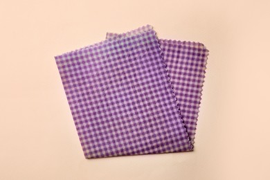Photo of Checkered reusable beeswax food wrap on beige background, top view