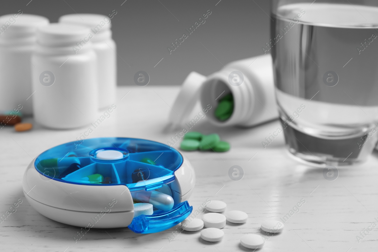 Photo of Pill box with medicaments on white wooden table, closeup