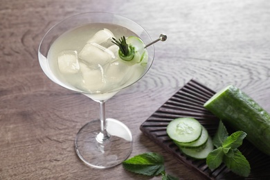 Photo of Glass of tasty cucumber martini and ingredients on wooden table