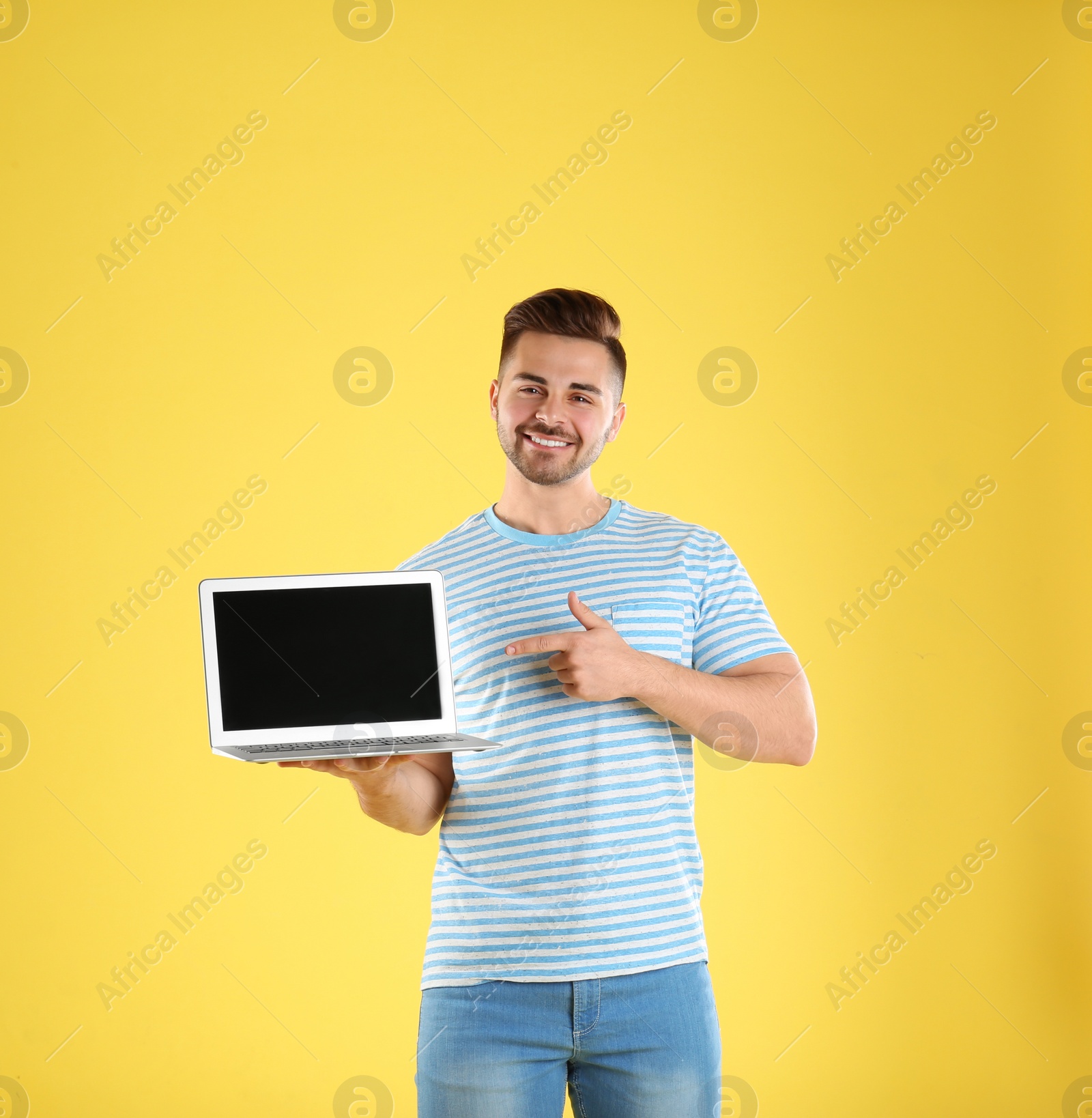 Photo of Happy man with laptop on yellow background. Space for text