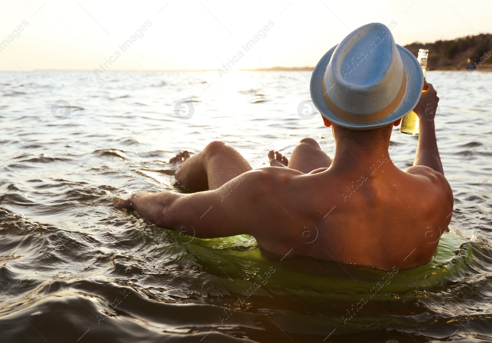 Photo of Young man with drink on inflatable ring in sea