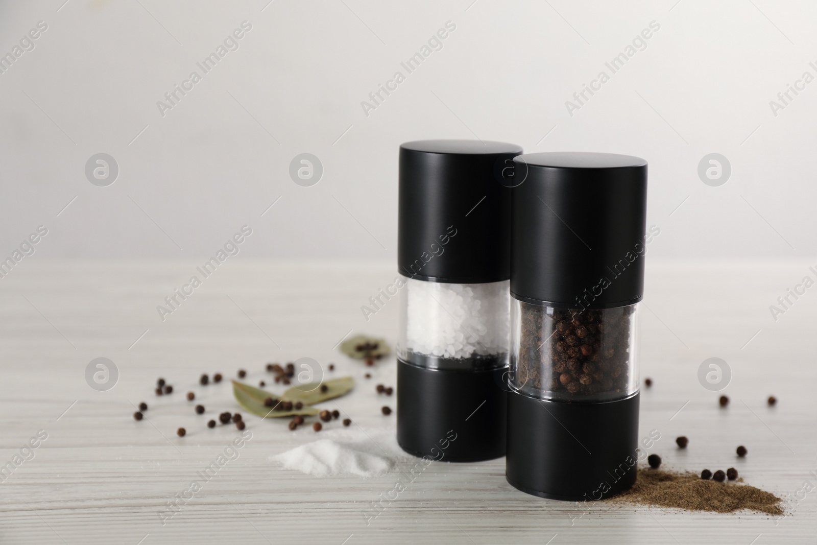 Photo of Salt and pepper shakers on white wooden table. Space for text