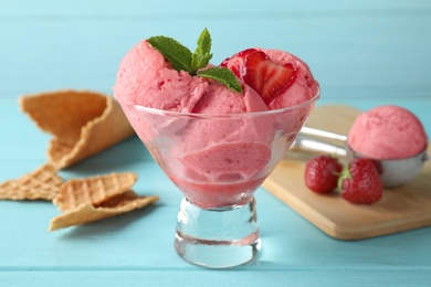 Delicious strawberry ice cream in dessert bowl served on light blue wooden table