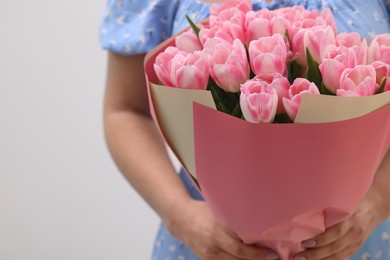 Woman with bouquet of beautiful fresh tulips on white background, closeup