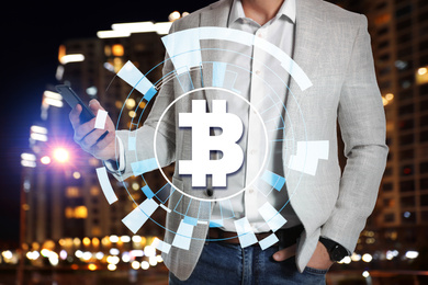 Image of Fintech concept. Scheme with bitcoin symbol and businessman using smartphone on cityscape background