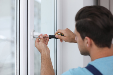 Construction worker repairing plastic window with screwdriver indoors