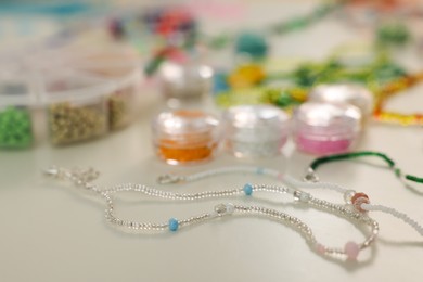Photo of Beautiful handmade beaded jewelry and supplies on white table