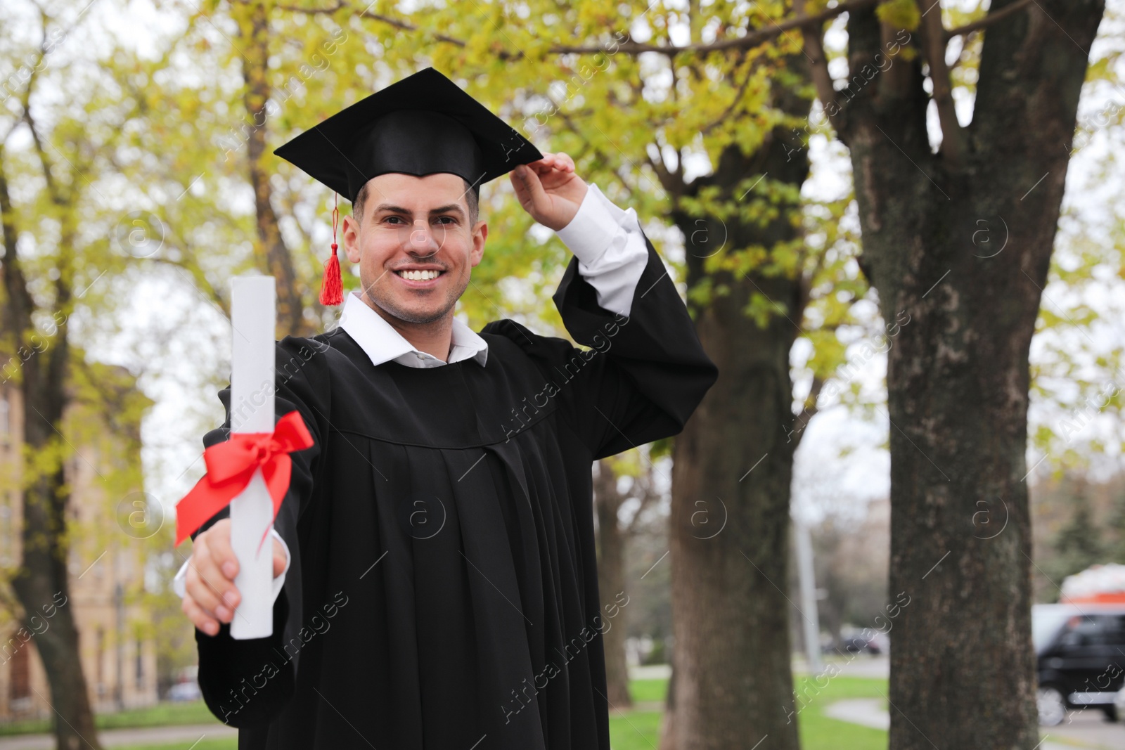 Photo of Happy student with diploma after graduation ceremony outdoors. Space for text