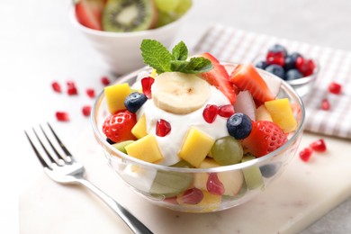 Photo of Delicious fruit salad with yogurt on light table
