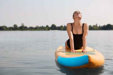 Photo of Woman practicing yoga on SUP board on river, space for text