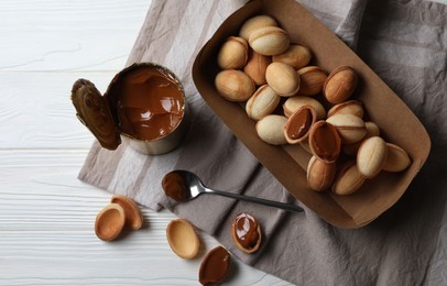 Delicious walnut shaped cookies with condensed milk on white wooden table, flat lay