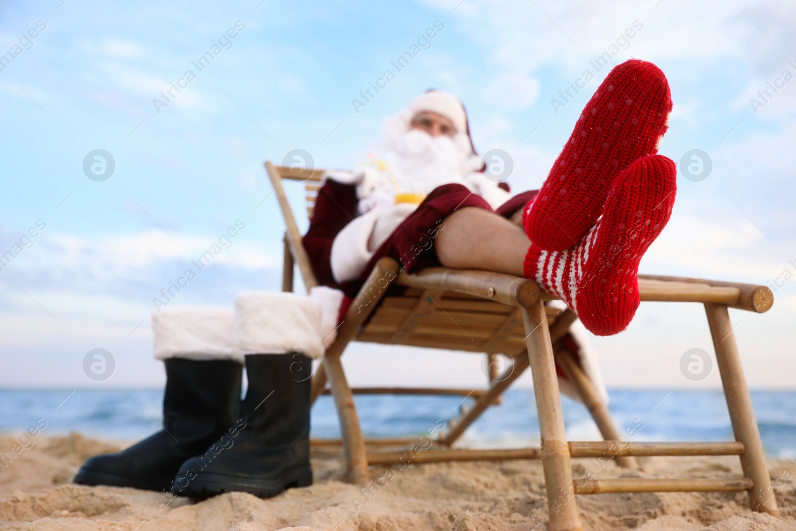 Photo of Santa Claus relaxing on beach. Christmas vacation