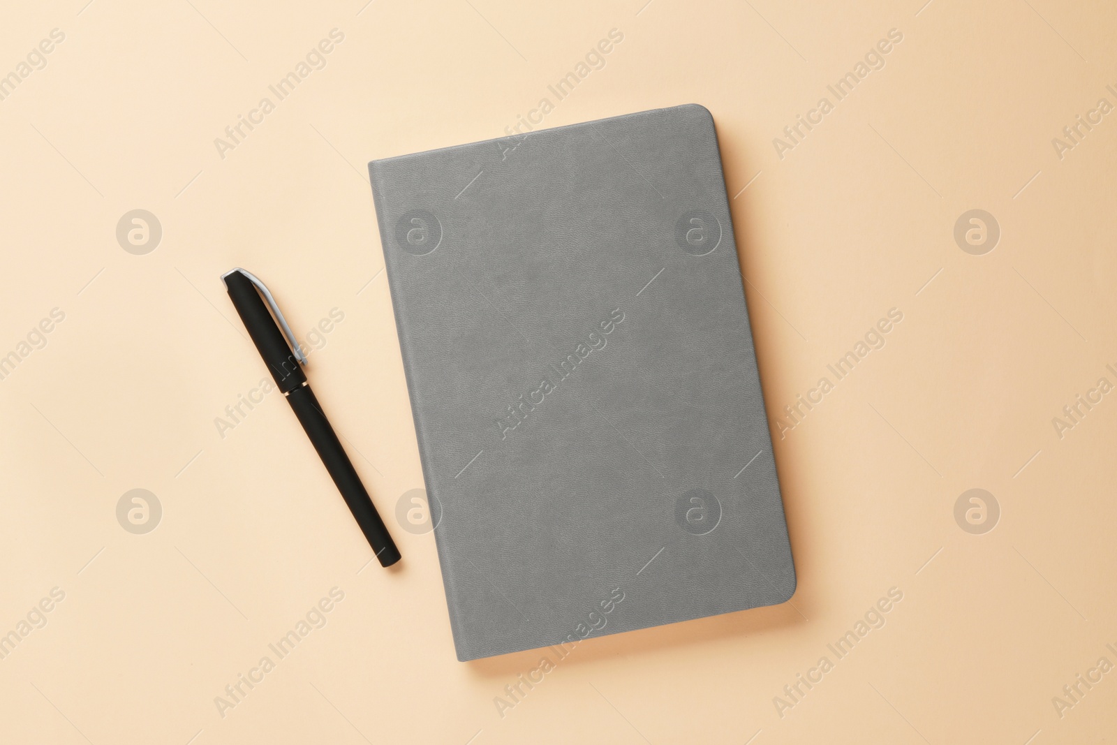 Photo of Gray notebook and pen on beige background, flat lay