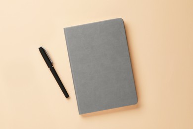 Gray notebook and pen on beige background, flat lay