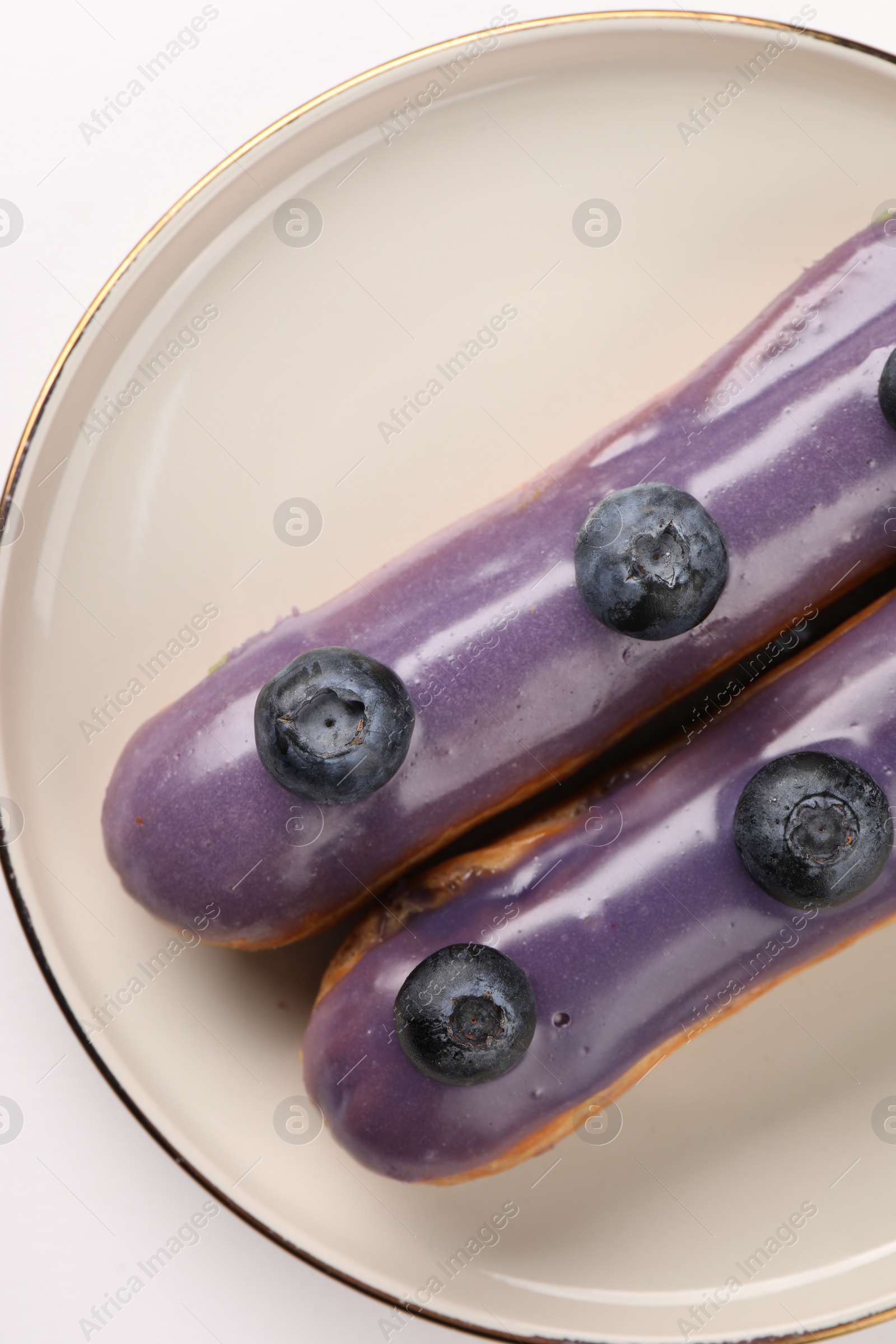 Photo of Delicious eclairs decorated with blueberries on white background, top view