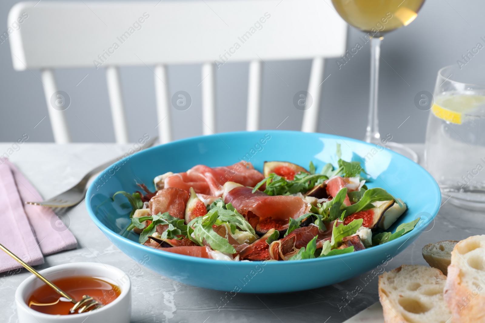 Photo of Salad with ripe figs and prosciutto served on grey marble table indoors