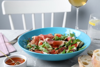 Salad with ripe figs and prosciutto served on grey marble table indoors