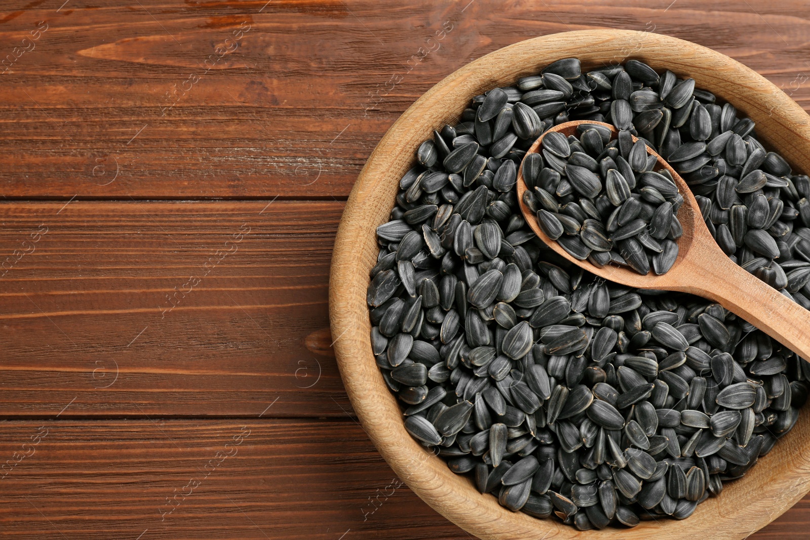 Photo of Bowl and spoon with sunflower seeds on table, top view