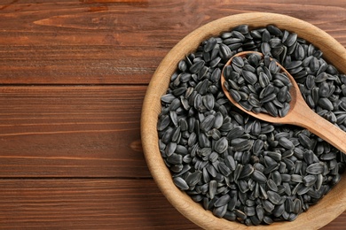 Photo of Bowl and spoon with sunflower seeds on table, top view