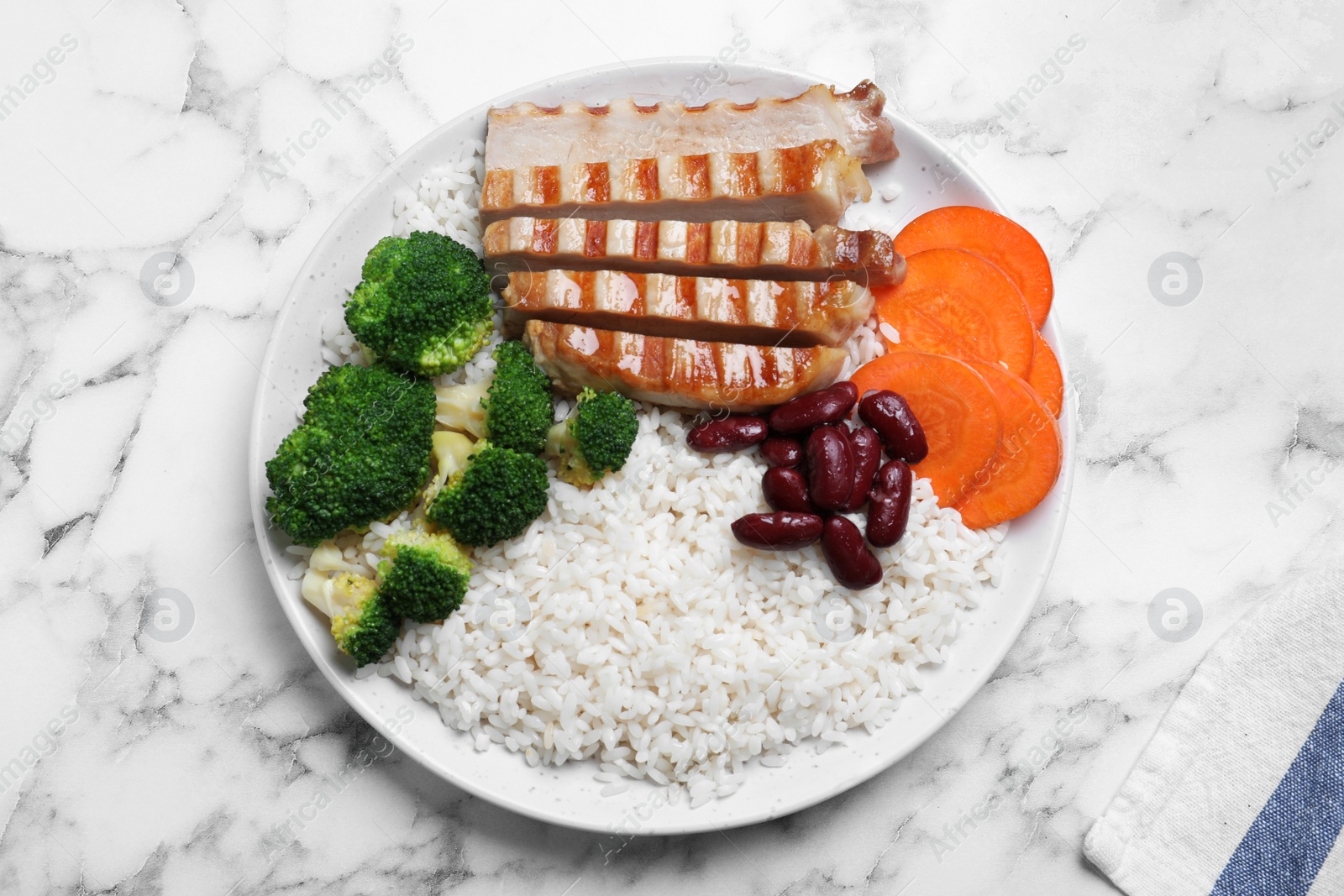 Photo of Delicious rice with beans and meat served on white marble table, top view