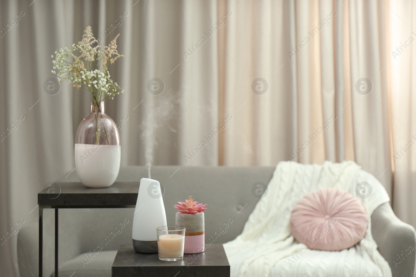 Photo of Aroma oil diffuser and candle on table in room