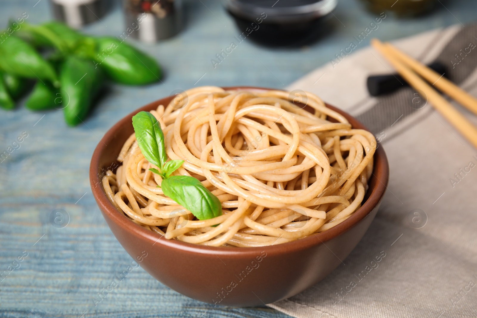 Photo of Tasty buckwheat noodles served on blue wooden table