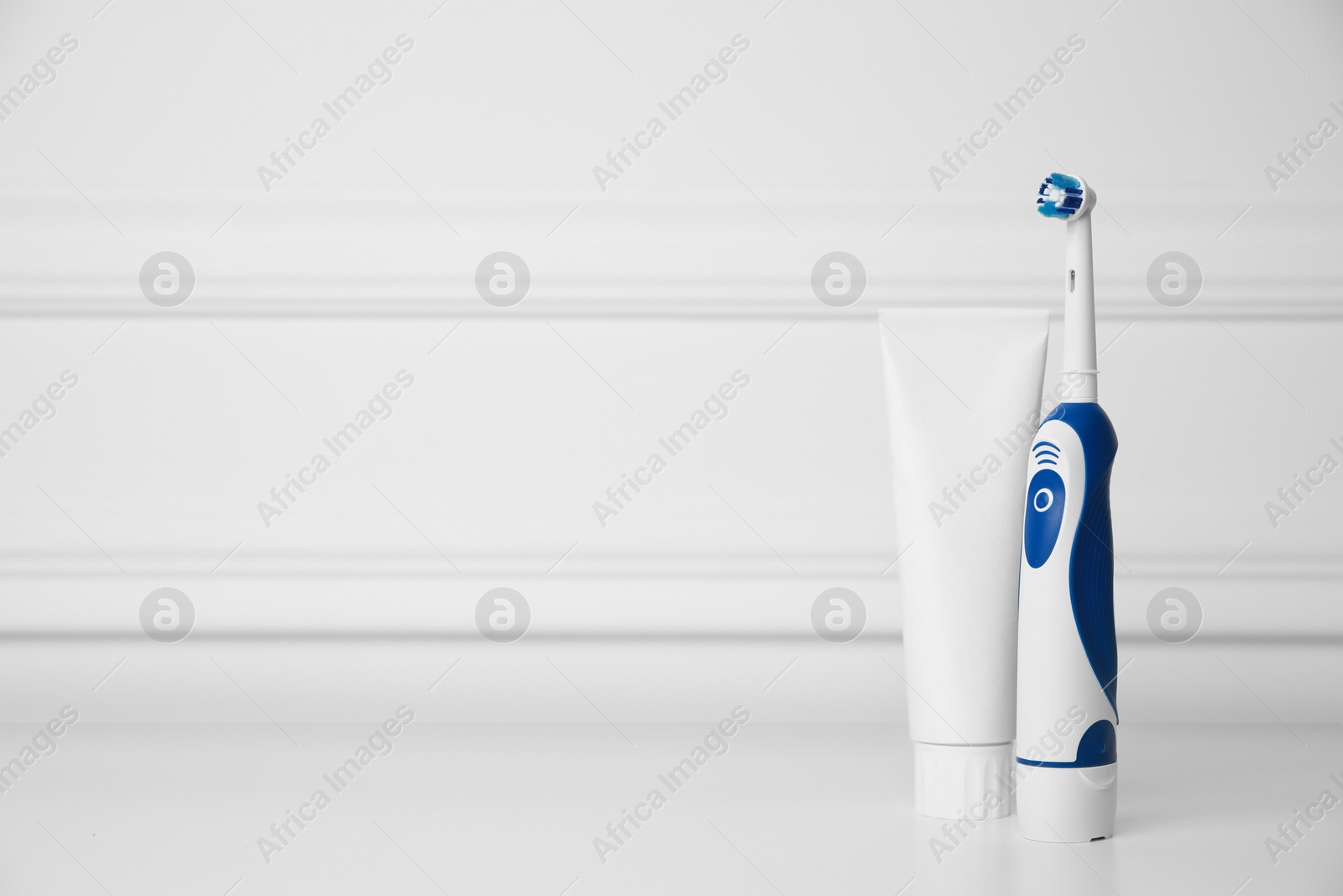 Photo of Electric toothbrush and toothpaste on white background, space for text