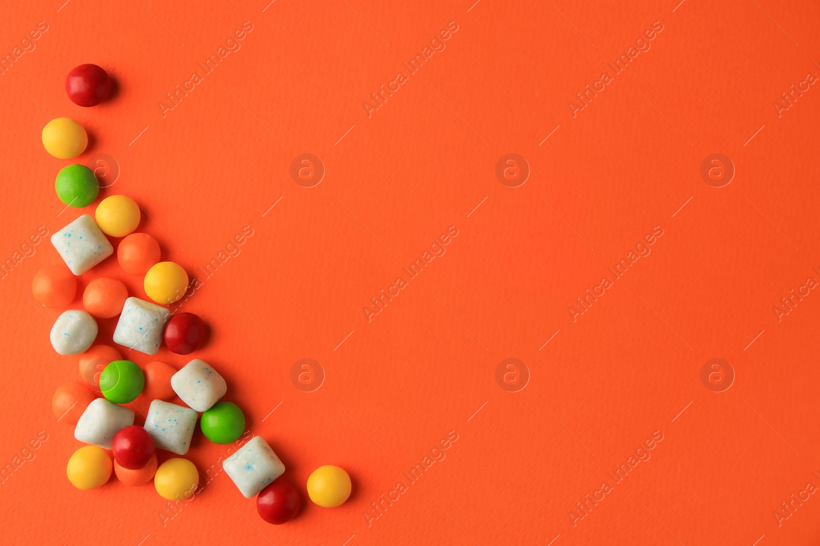 Photo of Different tasty chewing gums on orange background, flat lay. Space for text