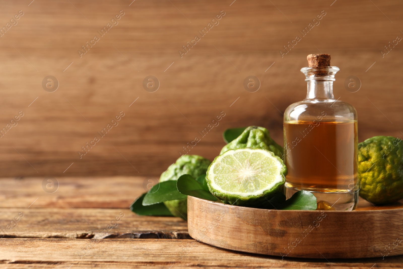 Photo of Glass bottle of bergamot essential oil on wooden table. Space for text
