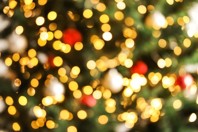 Blurred view of Christmas tree with bright fairy lights and ornaments, closeup. Bokeh effect