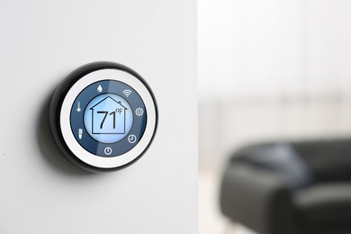 Image of Thermostat displaying temperature in Fahrenheit scale and different icons. Smart home device on white wall, space for text