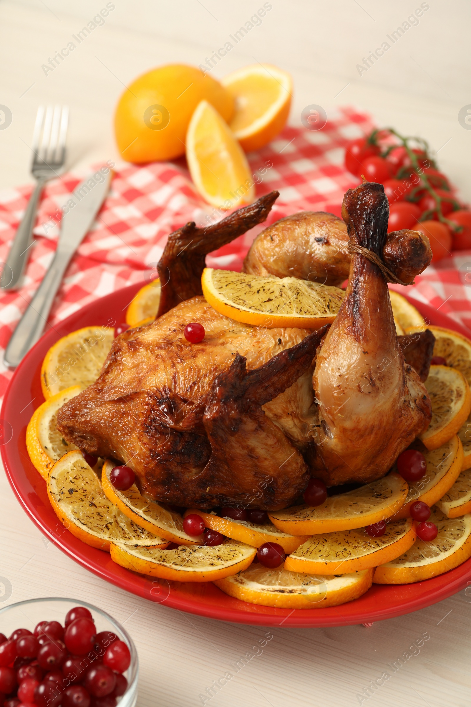 Photo of Baked chicken with orange slices on white wooden table, closeup