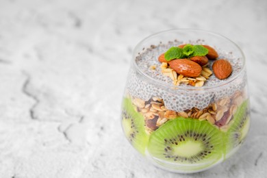 Photo of Delicious dessert with kiwi, chia seeds and almonds on light textured table, space for text
