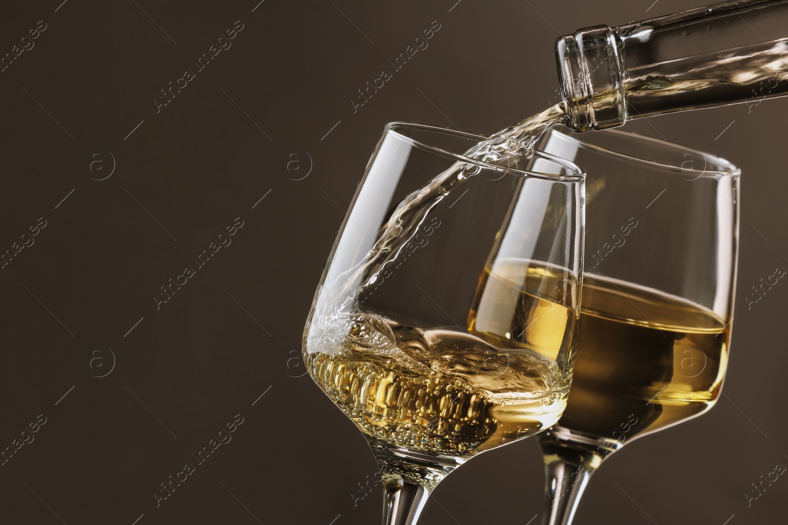 Photo of Pouring tasty aromatic wine in glass on gray background, closeup. Space for text